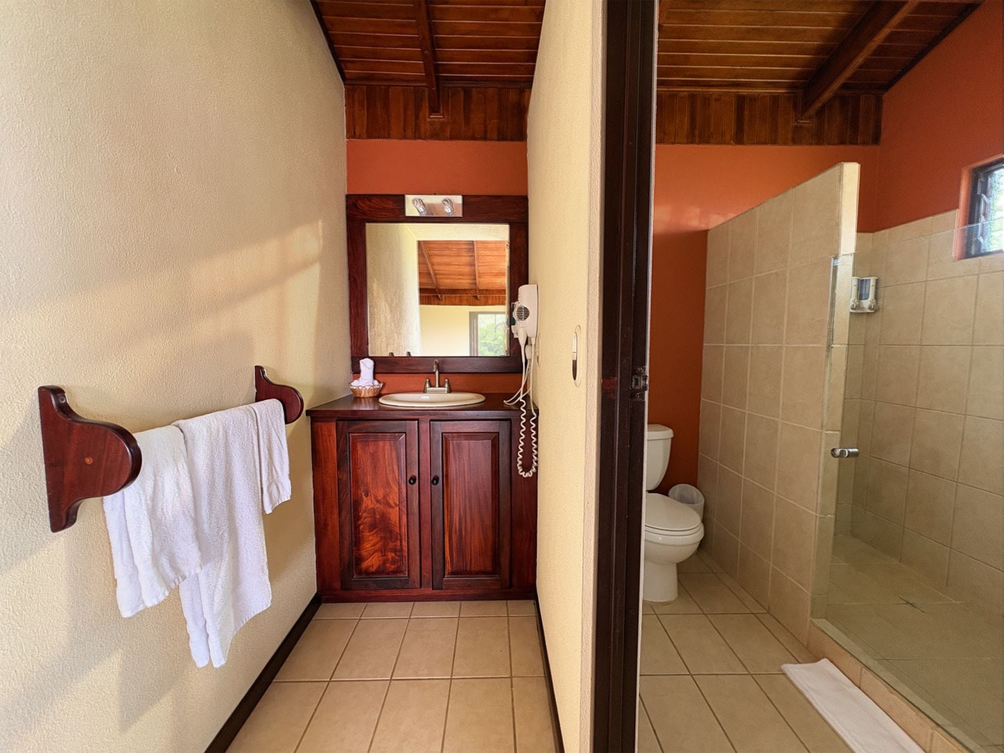 A bathroom with a wooden vanity, a toilet, and a glass shower enclosure.