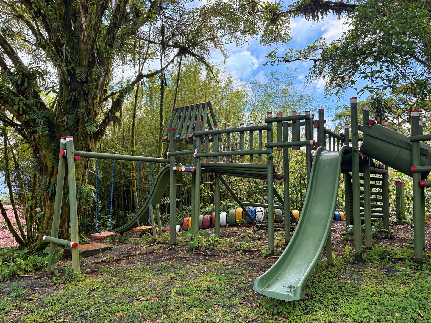 Ein Spielplatz mit Rutsche, Klettergerüsten und Schaukeln.