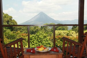 Uma mesa com uma travessa de fruta e vista para um vulcão.