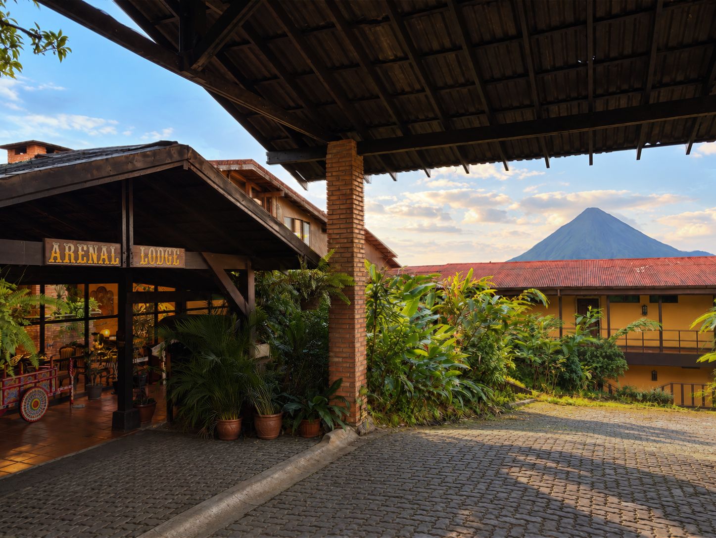 A lodge with a covered entrance, a brick chimney, and a view of a mountain.