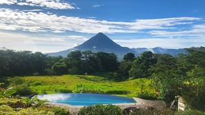A pool surrounded by lush greenery and a mountain in the background. - Hotel Arenal Lodge (La Fortuna)