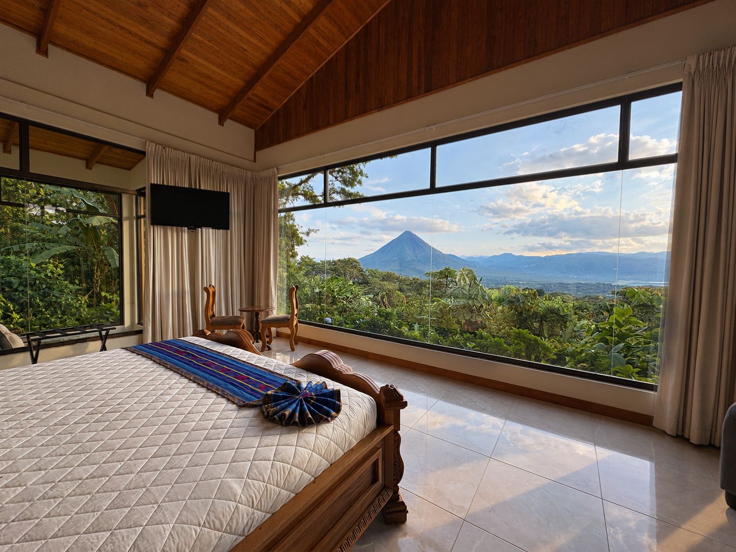 A bedroom with a large bed, a TV, and a view of a mountain.