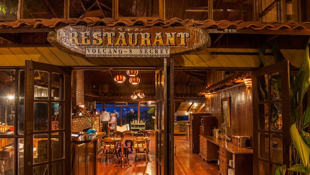Interior de restaurante con suelos de madera, una zona de bar y un comedor con mesas y sillas.