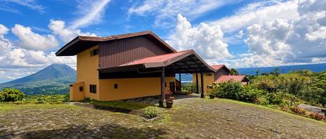 A two-story building with a covered patio and a mountain in the background.