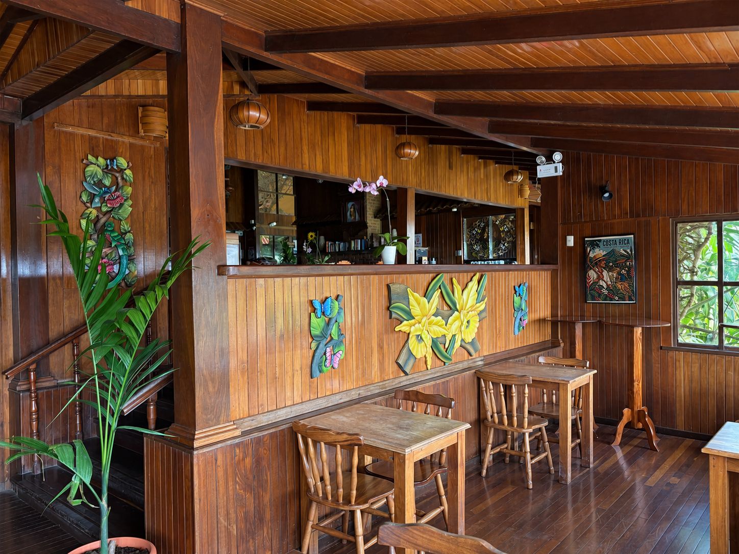 A wooden interior with a bar area, wooden chairs, and a large window.