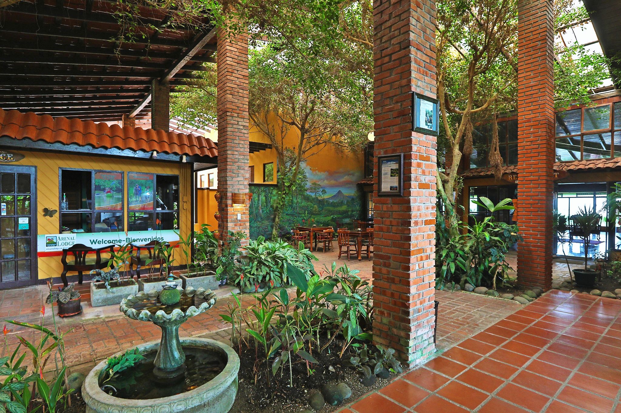 An indoor courtyard with a fountain, brick pillars, and a mural on the wall.