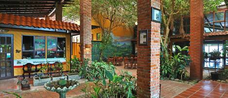 Un patio interior con una fuente, pilares de ladrillo y un mural en la pared.