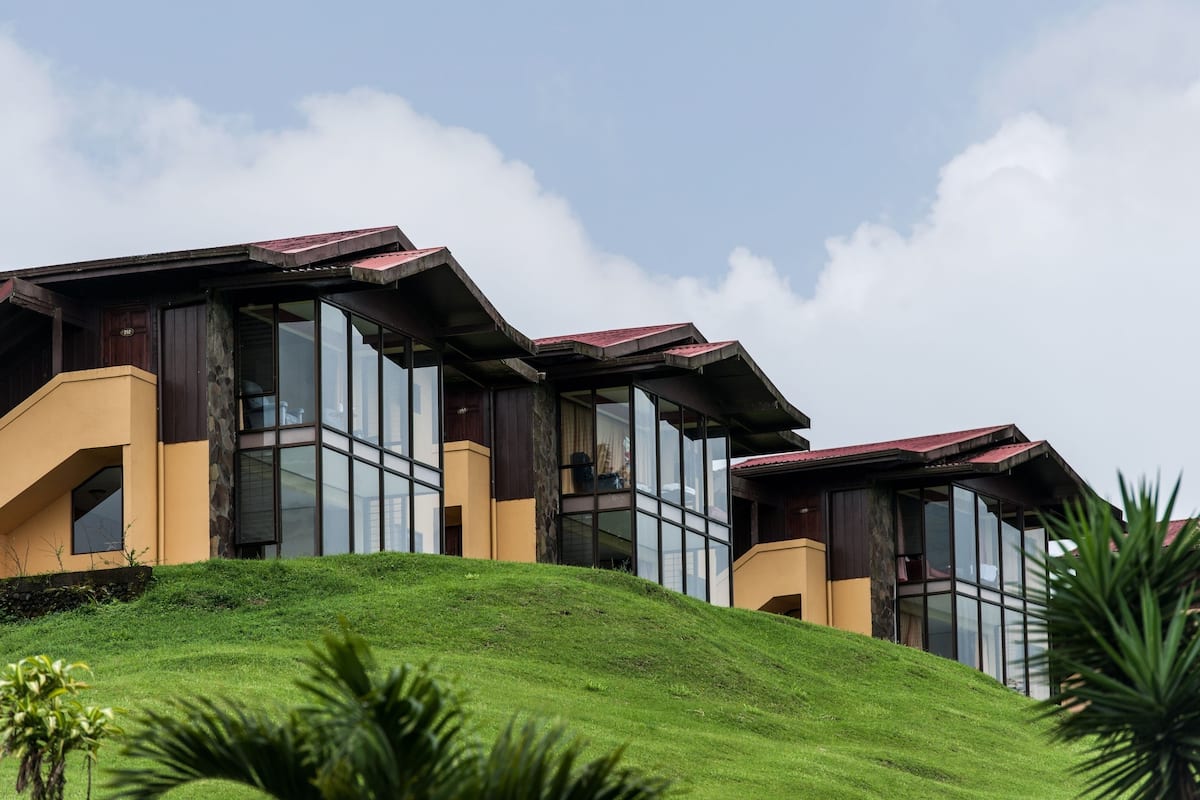 A modern building with large glass windows and a sloped roof, situated on a grassy hill.