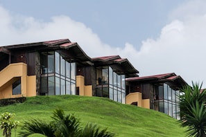 Un edificio moderno con grandes ventanales y techo inclinado, ubicado en una colina cubierta de césped.