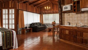 Amplia sala de estar con sofá, mesa de comedor y cocina con armarios de madera y microondas.