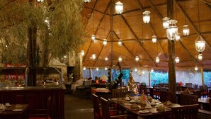 A restaurant with a high, wooden ceiling and hanging lights. Tables are set with plates and cutlery.