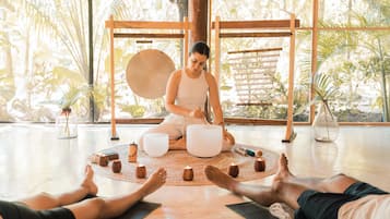 Find serenity in this peaceful space, featuring a meditation area with a large wooden structure and a gong, surrounded by potted plants and yoga mats.