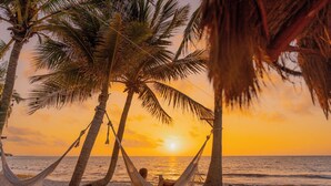 A hammock between palm trees on a beach at sunset. - Petit Lafitte Beachfront Hotel & Bungalows (Playa del Carmen)
