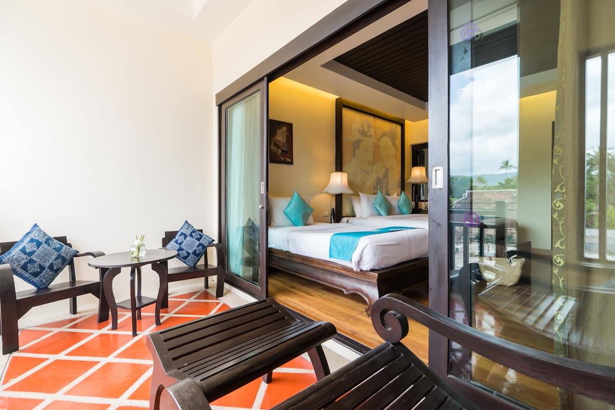 A hotel room with a bed, a sitting area with a table and chairs, and a view through a glass door.