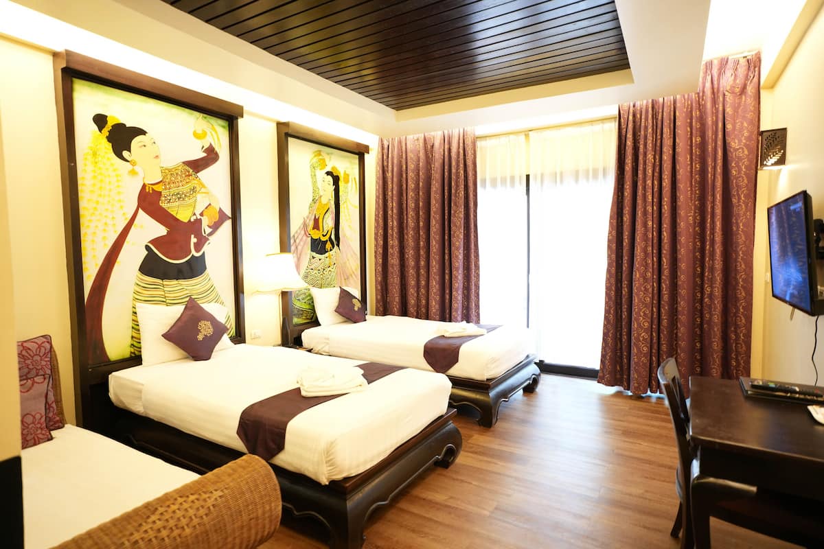 A hotel room with two beds, a desk, a television, and artwork on the walls.