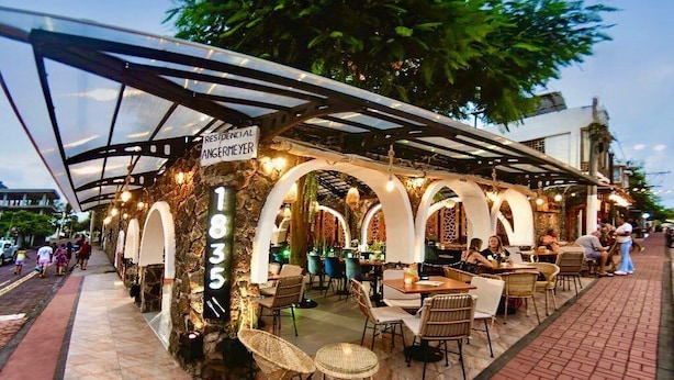 An outdoor restaurant with a covered patio, stone walls, and outdoor seating. - Hotel Silberstein (Puerto Ayora)