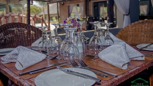 A dining table set for four with clear glassware, white napkins, and silverware. - Chrismar Hotel Livingstone (Livingstone)