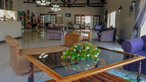 A spacious lobby with a glass coffee table, wicker furniture, and a large mirror. - Chrismar Hotel Livingstone (Livingstone)