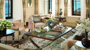 A spacious living room with a large chandelier, comfortable seating, a coffee table with decorative items, and large windows offering a view of the sea. - Four Seasons Hotel Istanbul at the Bosphorus (Istanbul)