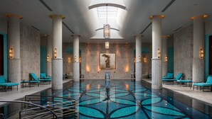 A spacious indoor pool area with a geometric tile design, large columns, and lounge chairs. - Four Seasons Hotel Istanbul at the Bosphorus (Istanbul)