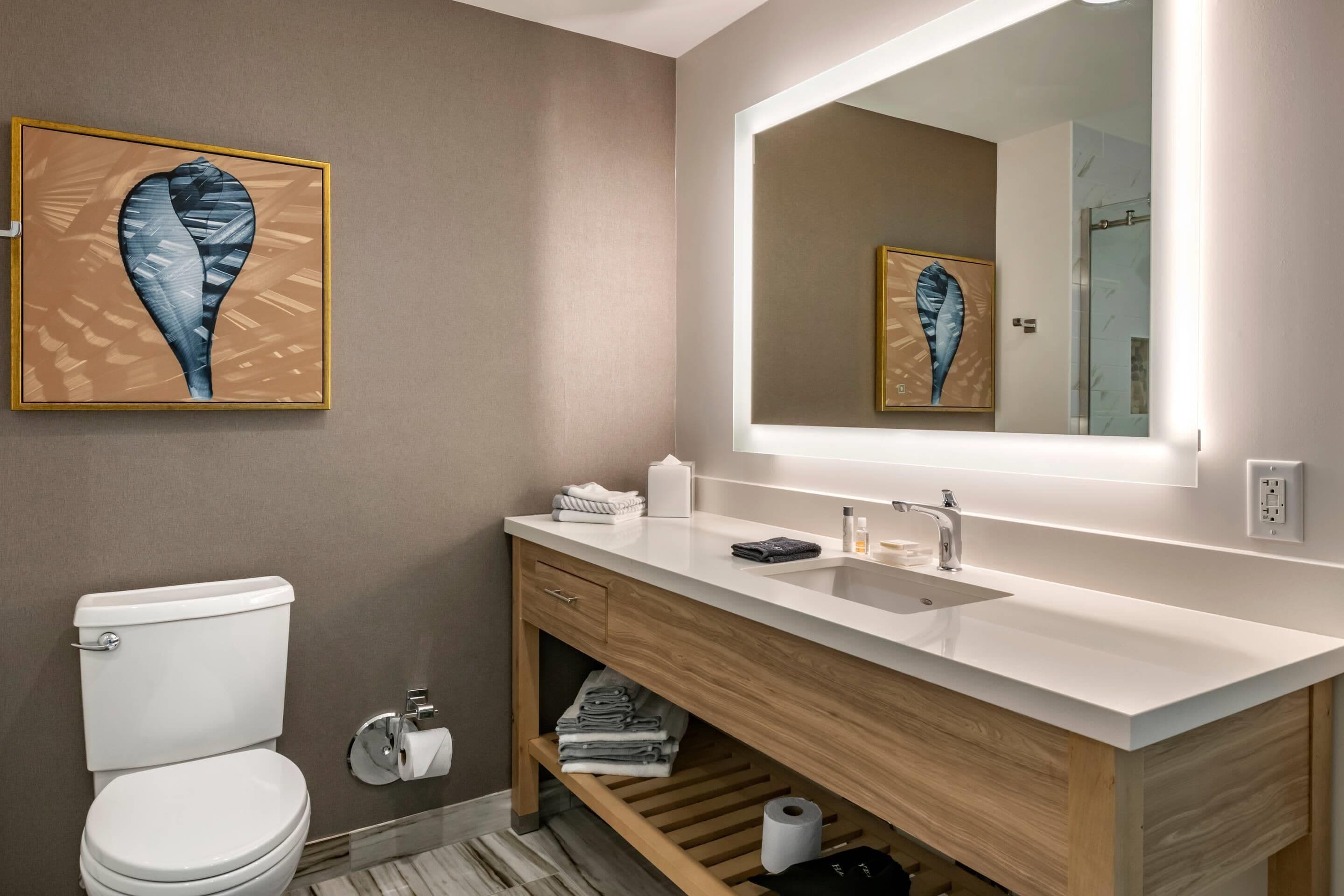 Ein modernes Badezimmer mit Toilette, Holzwaschtisch und großem Spiegel.