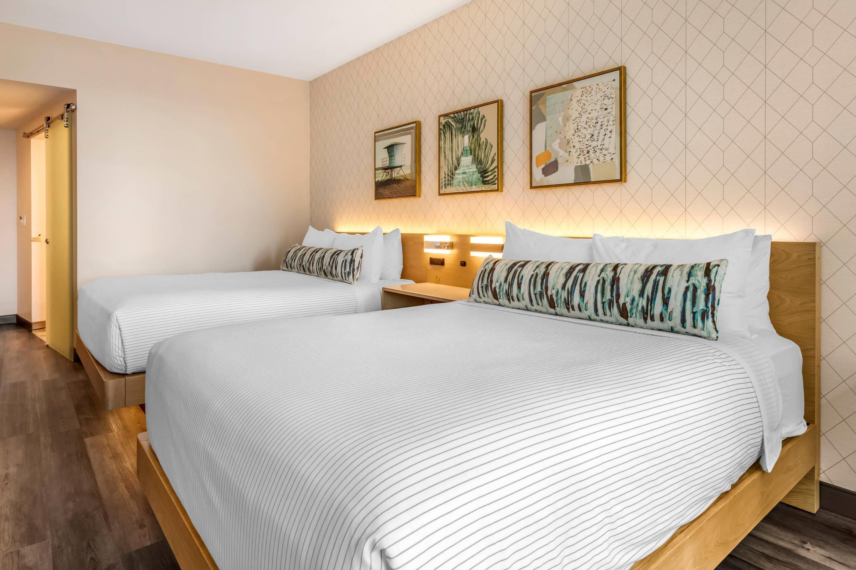 A hotel room with two beds, wooden headboards, and a patterned wall.