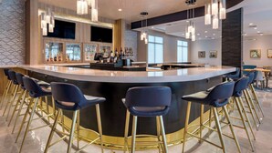 Un espace bar moderne doté d’un comptoir incurvé, de tabourets de bar et de luminaires suspendus.
