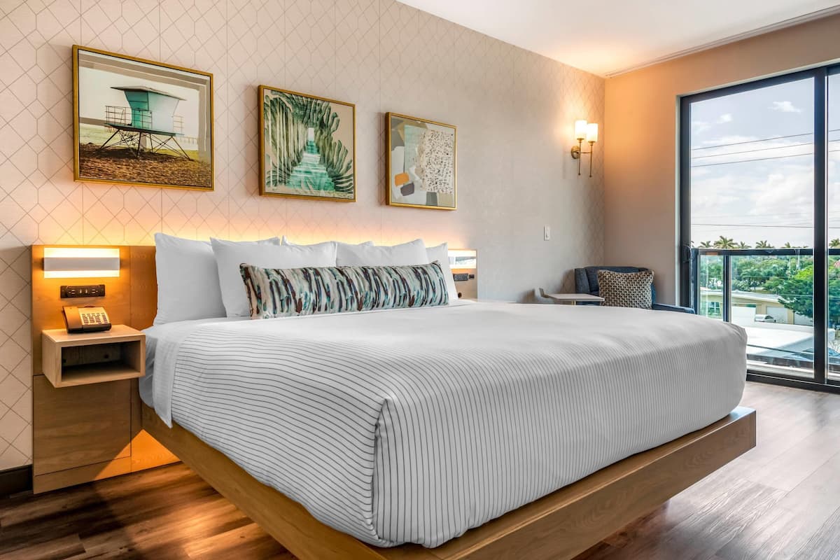 Una habitación de hotel moderna con una cama grande, mesitas de noche y obras de arte en las paredes.