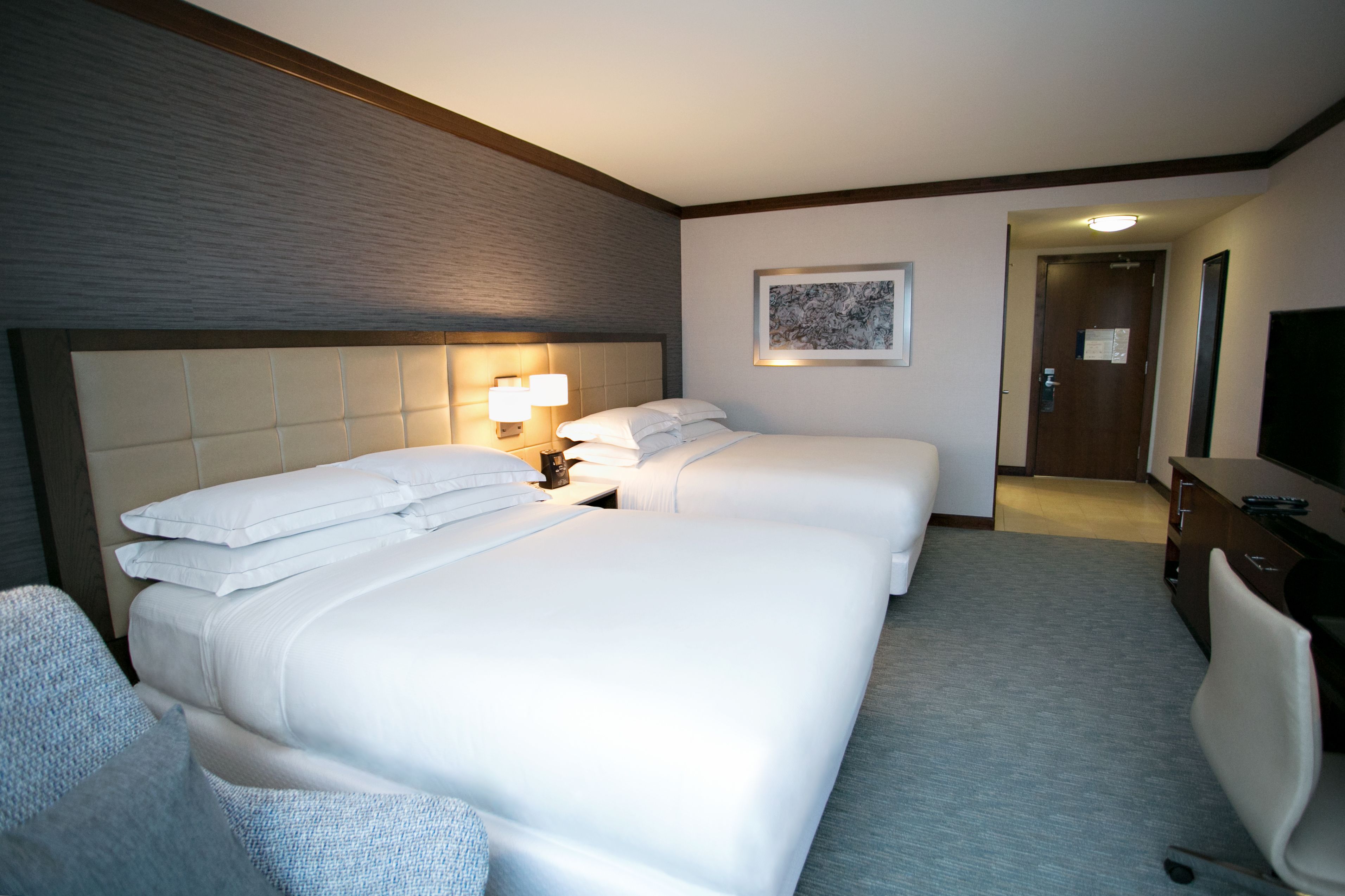 Ett hotellrum med två sängar, ett skrivbord, en stol och en tv.