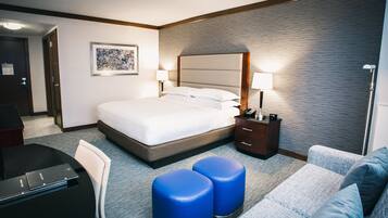 A hotel room with a bed, bedside tables, a desk, and a sofa.