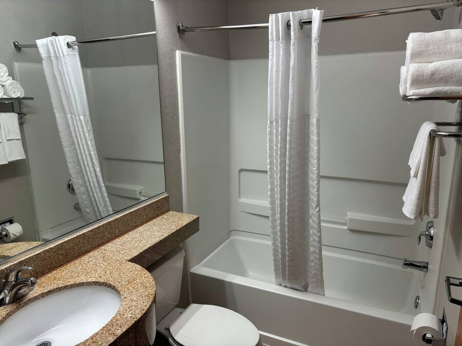A bathroom with a sink, toilet, bathtub, and shower curtain.