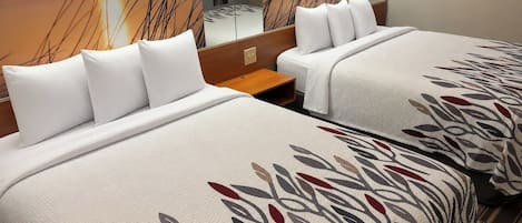 Een hotelkamer met twee bedden, elk voorzien van witte beddengoed en een plaid met bladmotief.