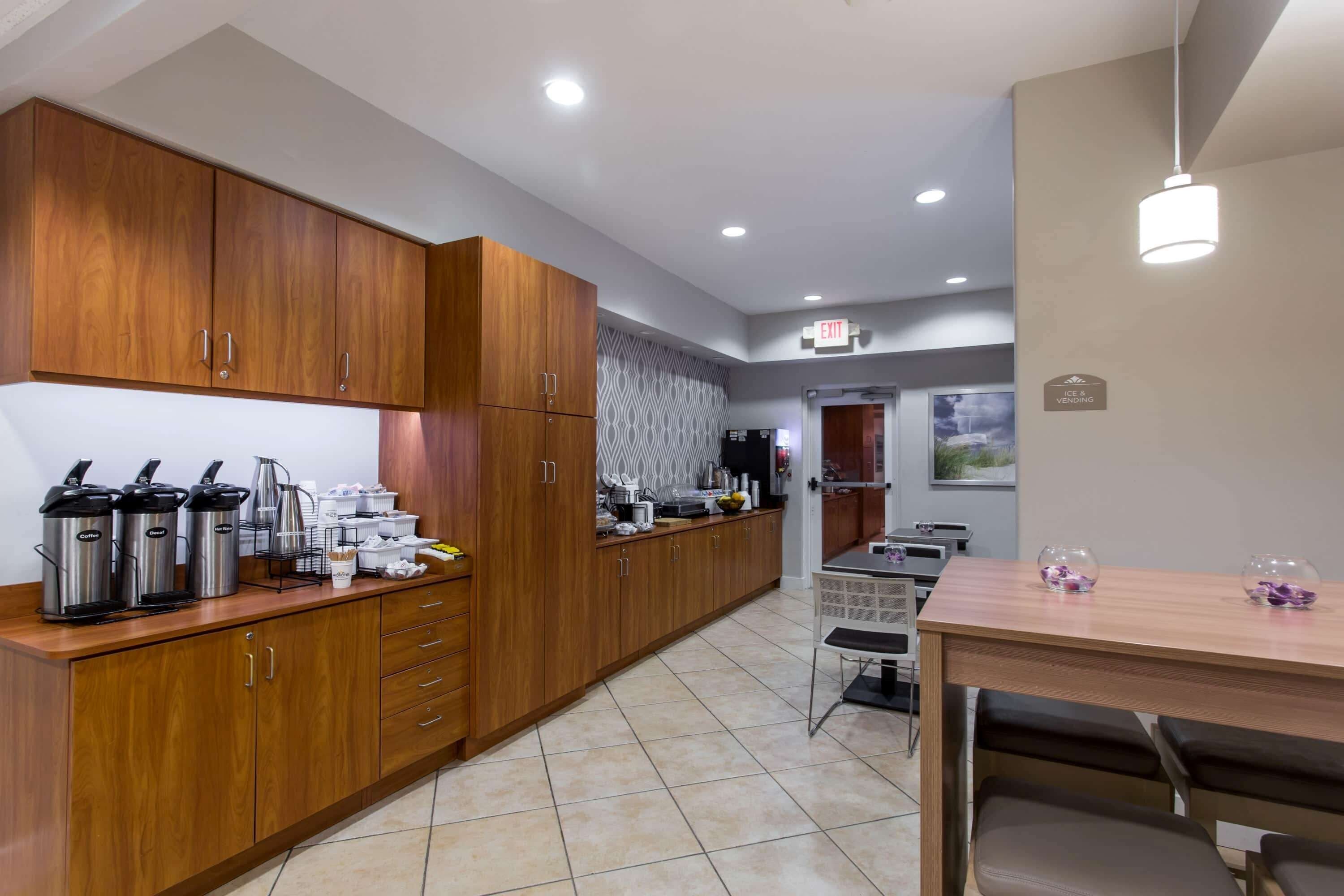 A modern kitchen with wooden cabinets, stainless steel appliances, and a dining area with a table and chairs.
