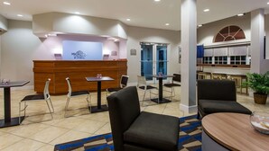 A hotel lobby with a reception desk, several tables and chairs, and a large window with a view. - Microtel Inn & Suites by Wyndham Port Charlotte/Punta Gorda (Port Charlotte)