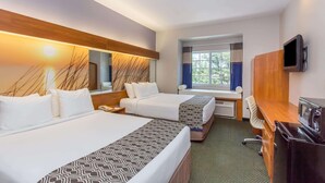 A hotel room with two beds, a desk, a TV, and a window with curtains. - Microtel Inn & Suites by Wyndham Port Charlotte/Punta Gorda (Port Charlotte)