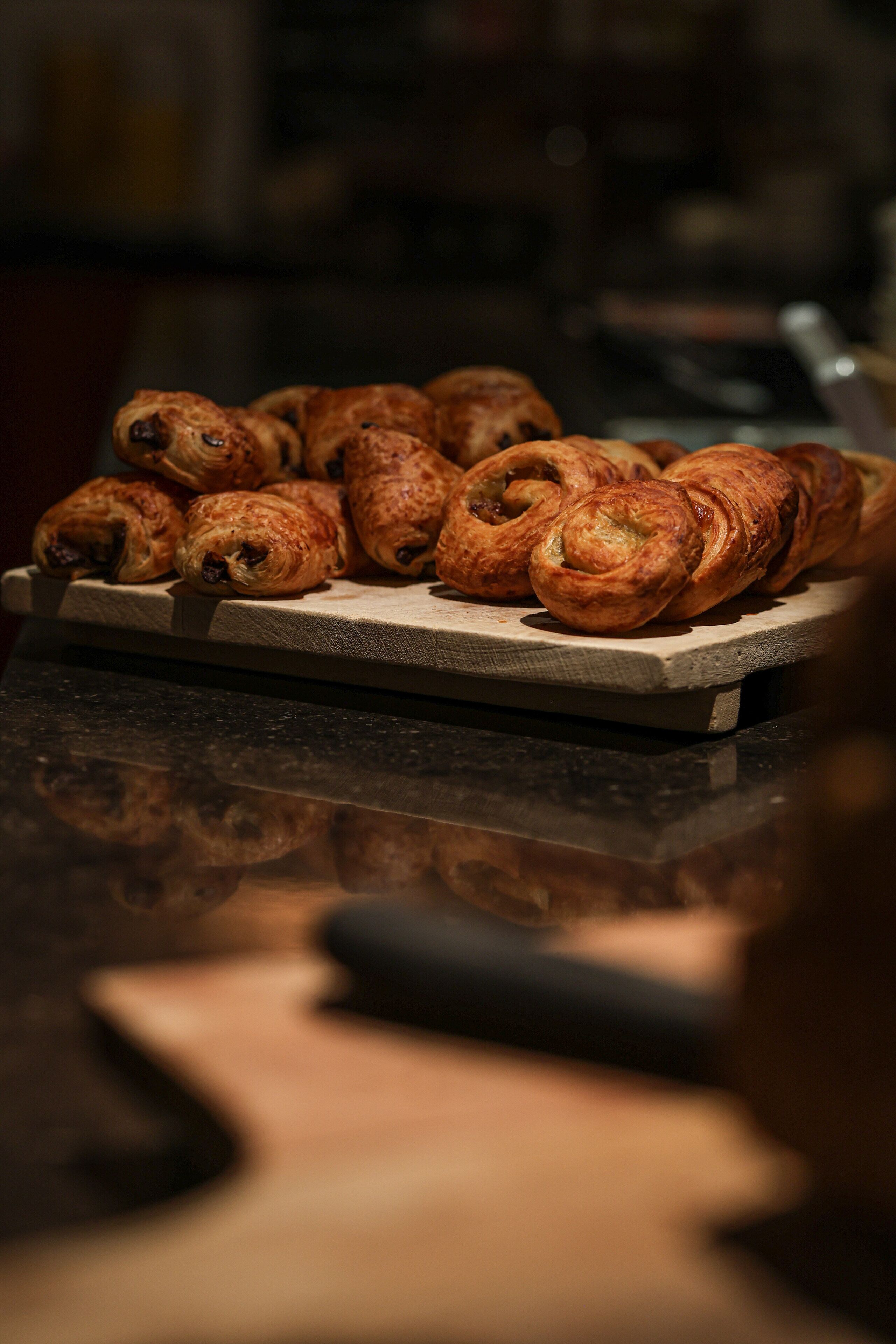 A wooden cutting board with croissants on a kitchen counter.