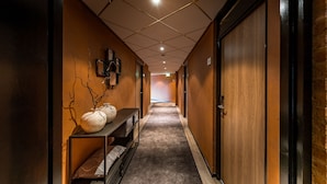 Een gang met houten wanden, een donker vloerkleed en een plank met decoratieve objecten.