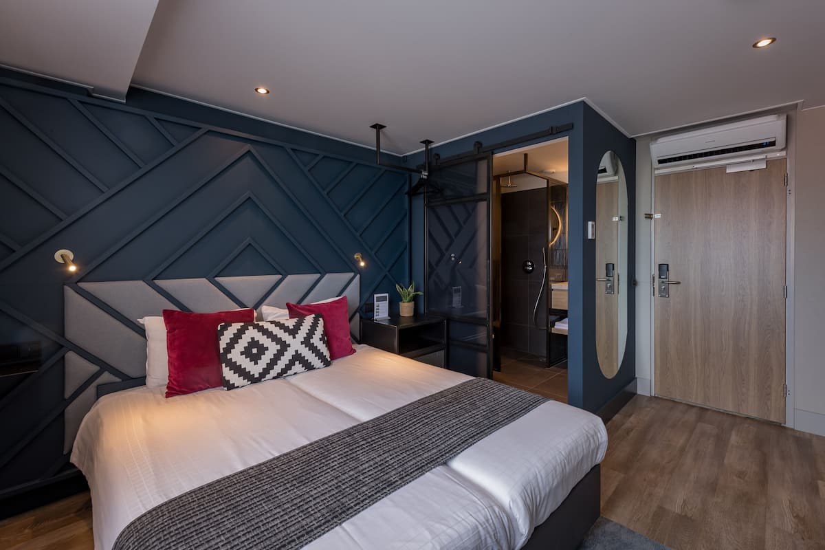 Een moderne slaapkamer met een groot bed, een geometrisch wandontwerp en een inloopkast.