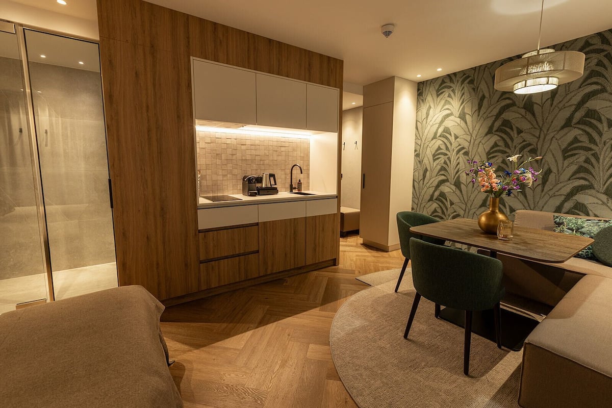 Een moderne keuken met houten kastjes, een inbouwgootsteen en een eethoek met tafel en stoelen.