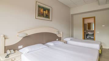Ein Hotelzimmer mit zwei Betten, einem Nachttisch mit Telefon, einem Bild an der Wand und einem durchgegangenen Tür erkennbaren Badezimmer.