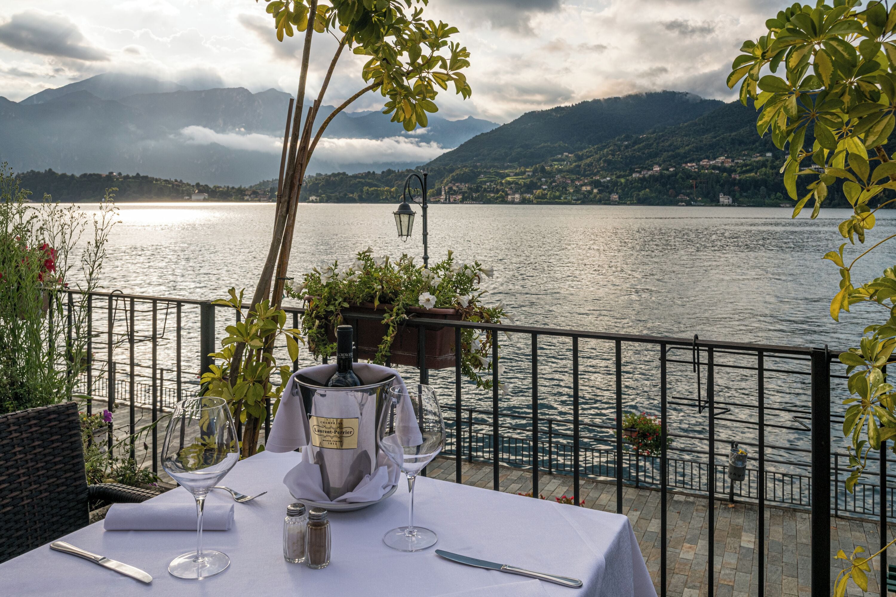 A table set for dining with a view of a lake and mountains.