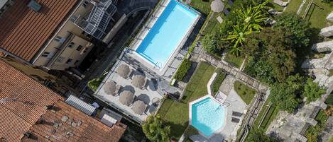 An aerial view of a hotel with a swimming pool, outdoor seating, and lush landscaping.