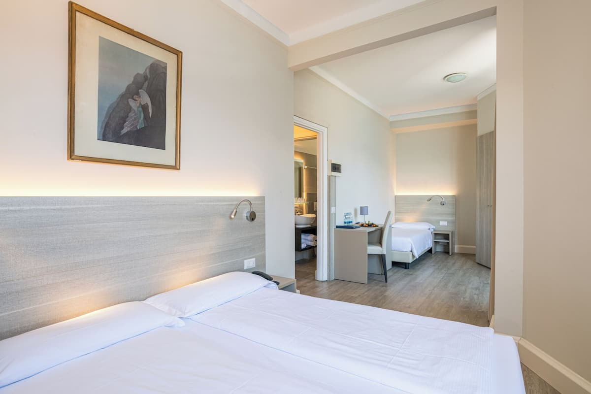 A hotel room with a large bed, a desk, and a bathroom visible through an open door.