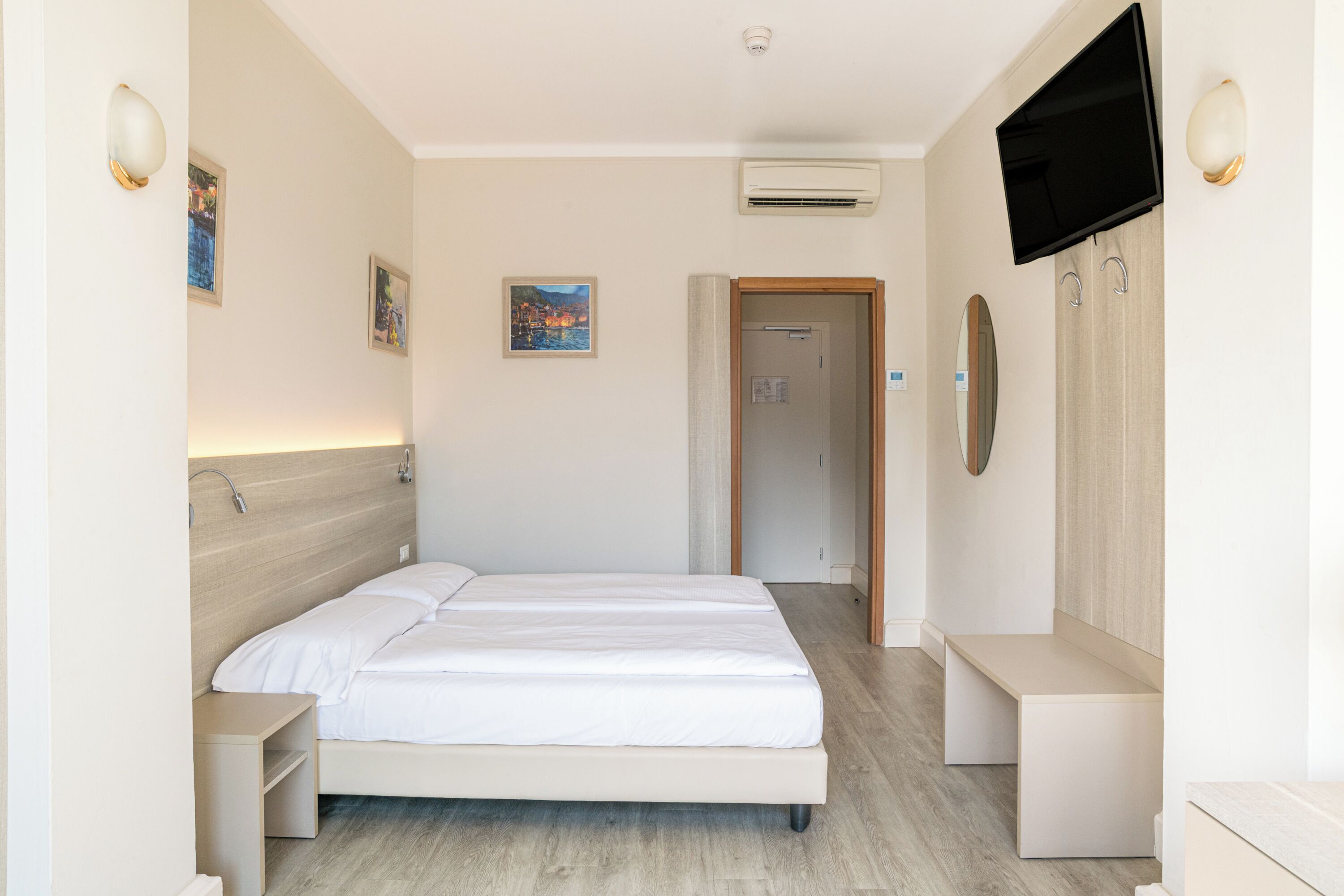 A hotel room with a bed, bedside tables, a TV, and a wardrobe.