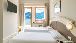 Habitación de hotel con dos camas, un escritorio, una silla, un televisor y vista a las montañas.