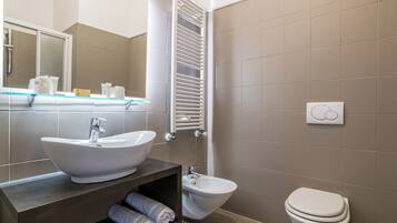 Een moderne badkamer met een wastafel, toilet en bidet.