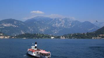 Una barca con un tetto a righe rosse e bianche che si muove su un lago, con montagne sullo sfondo.