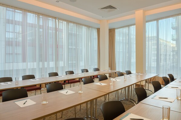 Un salón de conferencias con una larga mesa, sillas y un amplio ventanal con cortinas.