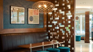 A modern interior with a wooden bench, a table, and teal ottomans.