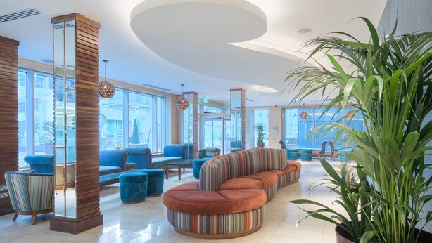 A spacious lobby with a curved seating area, large windows, and a potted plant.